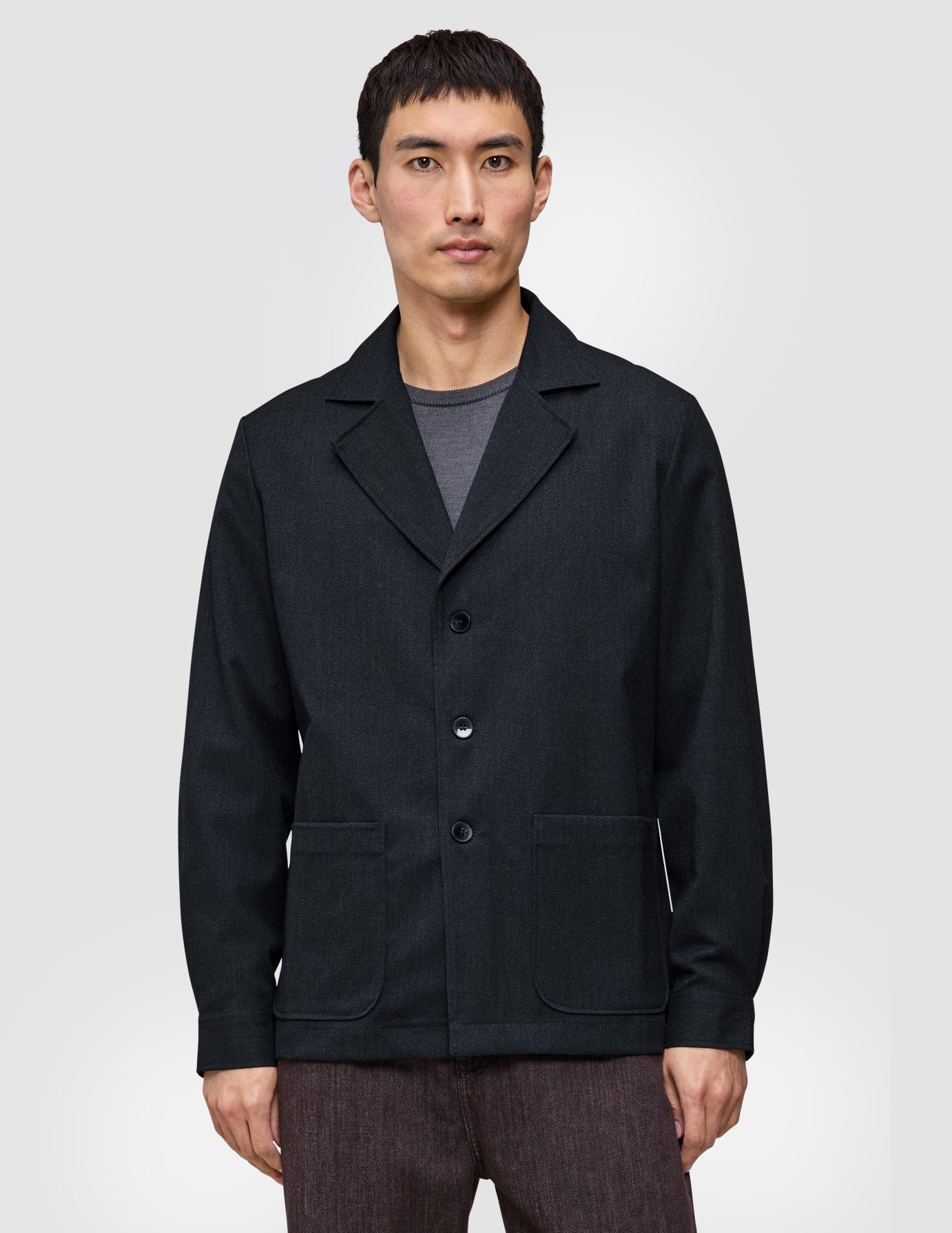 En mand iført en mørk marineblå Atelier Overshirt med en krave med udskæring og to påsatte lommer foran.